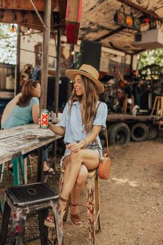 a woman sitting at a table with a beer in her hand