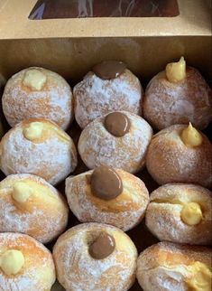 a box filled with lots of powdered doughnuts covered in icing and chocolate