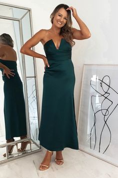 a woman standing in front of a mirror wearing a green dress