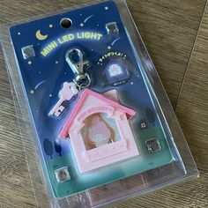 a pink house shaped keychain with a light on it's side in a package