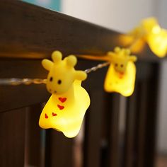 some yellow lights are hanging from a wooden railing with giraffes on them