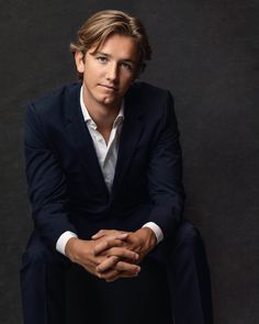 a man in a suit sitting down with his hands on his knees