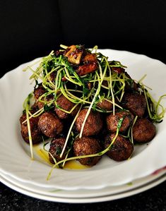 a white plate topped with meat and veggies on top of a black table