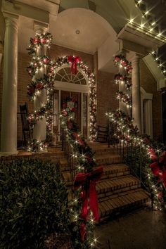 christmas decorations on the front steps of a house with red bows and lights around them