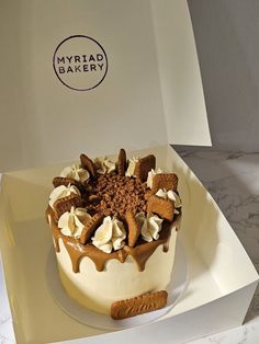 a cake with white frosting and chocolate toppings in a box on a table