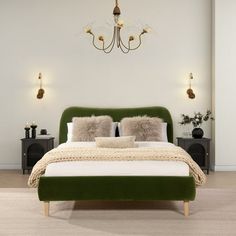 a green bed with two pillows on it and a chandelier hanging from the ceiling