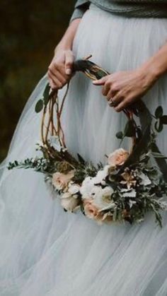 a woman in a white dress holding a flower wreath