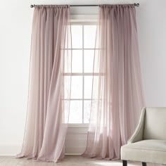 a chair sitting in front of a window next to a white wall with curtains on it