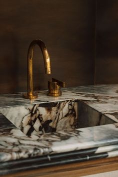 a marble sink with gold faucet and matching faucets in a bathroom