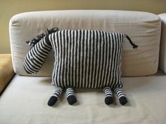 a black and white striped pillow sitting on top of a couch next to a wall