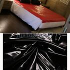 there is a bed with black and white sheets on it, next to a red and white bedspread