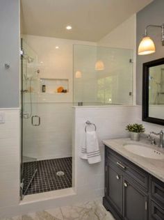 a bathroom with a walk in shower next to a white sink and black cabinetry