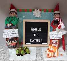 two elfs sitting next to each other near a sign that says would you rather eat chocolate?