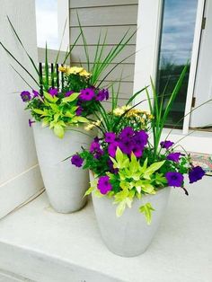 two white vases filled with purple and yellow flowers sitting on a step next to a door