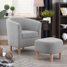 a grey chair and ottoman in a living room with bookshelf behind the chair