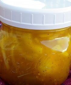 a jar filled with yellow liquid sitting on top of a purple table cloth next to a white lid