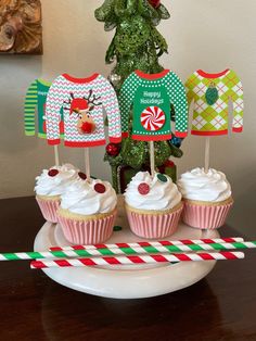 some cupcakes are sitting on a plate with christmas sweaters and candy canes