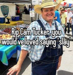 a man wearing overalls and a cowboy hat standing in front of an outdoor market