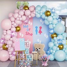 a teddy bear sitting in front of a balloon arch with balloons and other decorations around it