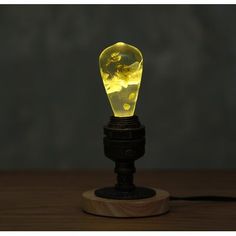 a yellow light bulb sitting on top of a wooden table