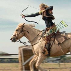 a woman is riding a horse with an arrow in her hand