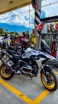 two motorcycles are parked next to each other at a gas station