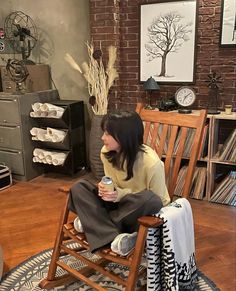 a woman sitting in a rocking chair holding a cup