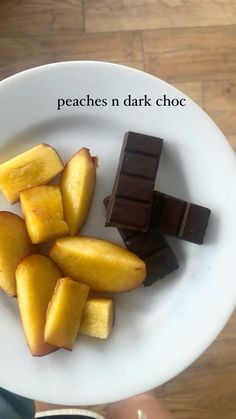 a white plate topped with pieces of fruit and chocolate on top of a wooden table