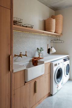 a washer and dryer in a small room with wooden shelves above the sink