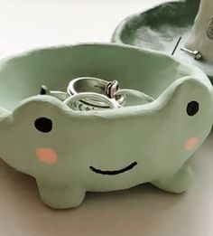 a green elephant shaped ring holder with two rings in it's mouth and a plate behind it