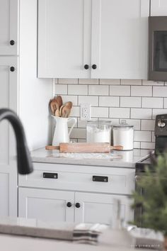 a kitchen with white cabinets and wooden utensils on the counter top next to an oven