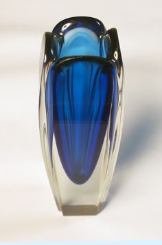 a blue glass vase sitting on top of a white table