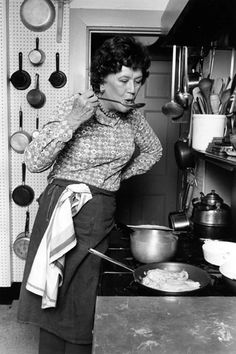 an old black and white photo of a woman cooking