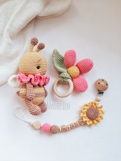 two crocheted toys and a wooden bead ring on a white surface with a flower