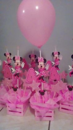 a table topped with lots of pink cupcakes and minnie mouse cake toppers