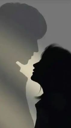 the silhouette of a man and woman kissing in front of a gray background with long shadows