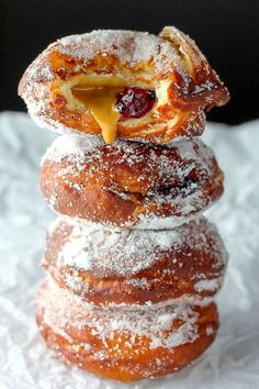 a stack of doughnuts sitting on top of each other covered in powdered sugar