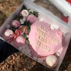 a pink heart shaped cake in a box with white frosting and decorations on it