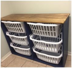 three white laundry baskets stacked on top of each other in front of a wooden counter