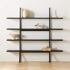 an empty shelf with books, vases and figurines on it in front of a white wall