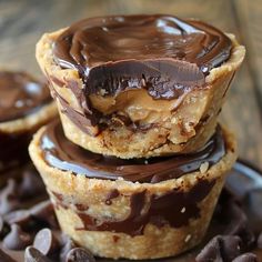 three chocolate covered desserts stacked on top of each other with chocolate chips around them