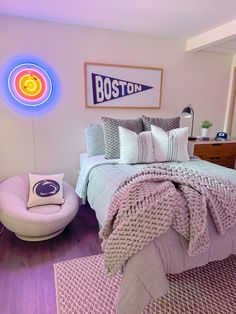 a bed room with a neatly made bed and a neon sign on the wall above it