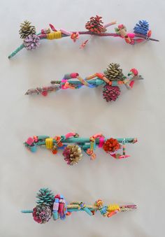 four pine cones are lined up next to each other on a white surface with colorful beads