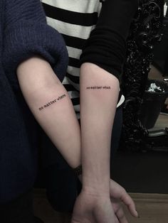 two people with matching tattoos on their arms, one is holding the other's arm