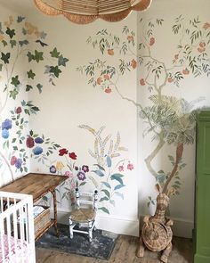 a baby's room with a crib and tree mural