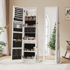 two tall white jewelry racks with mirrors on them in a living room next to a christmas tree