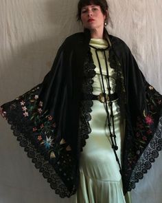 "Beautiful antique Victorian era black satin shawl with silk floral embroidery. Yellow tissue silk lining, two large braided tassel closures at the neckline, and a hook and eye closure below the bust. Black scalloped lace trim. The embroidery on this shawl is unreal and the colors are still extremely vibrant. There are even a few specs of pollen floating around! Measures 90\" x 46\". Condition: Great antique condition. Some fraying/snagging on embroidery, some lightened areas to black satin, and Luxury Black Embroidered Shawl, Elegant Luxury Shawl With Intricate Embroidery, Festive Black Shawl With Floral Embroidery, Black Embroidered Silk Shawl, Black Bohemian Shawl For Spring, Black Embroidered Shawl For Wedding, Black Bohemian Shawl With Embroidered Border, Bohemian Black Shawl With Embroidered Border, Traditional Black Shawl With Floral Embroidery