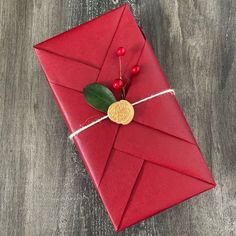 a red envelope with a gold heart and holly on it, tied to a wooden table