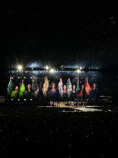 a group of people standing on top of a stage under bright lights in the dark