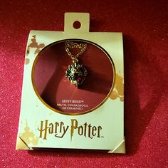 the harry potter necklace is on display in a box with its tag hanging from it's side